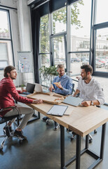 young businessmen eating pizza at workplace