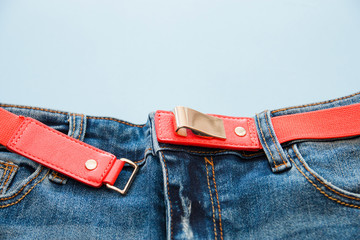 blue jeans with a red strap on the waist on blue background