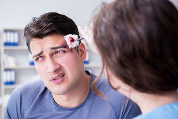 Young man visiting female traumatologist with black eye 