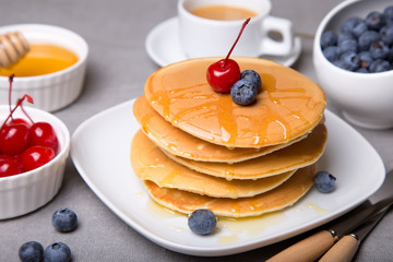 Pancakes with blueberries, cherries and honey. Close-up. Selective focus.