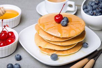 Pancakes with blueberries, cherries and honey. Close-up. Selective focus.