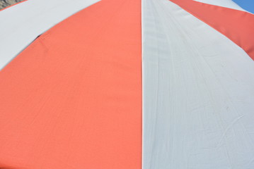 Beach umbrella white and red in the form of triangles, rest on the beach of the Black Sea