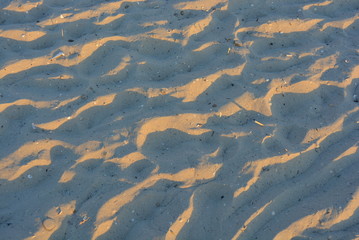 Yellow sand of the black sea at sunset with a blue shadow and golden color, very ordinary background