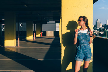 Girl in a jeans overalls looking left in the parking