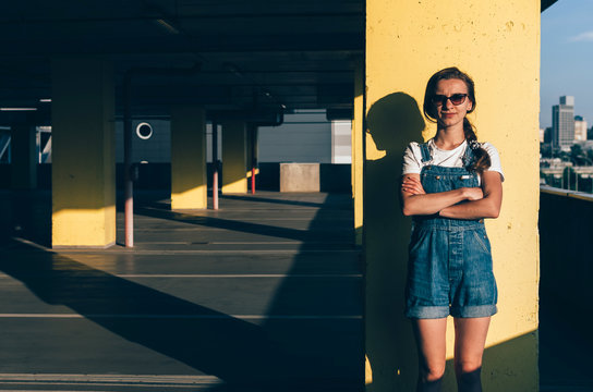 Young Girl in a jeans overalls looking straight in the parking