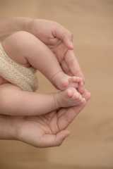 Feet of a newborn baby in the hands of parents. Happy Family oncept. Mum and Dad hug their baby's legs.
