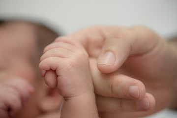 Newborn baby holding finger of mother / father. Happy Family and Baby protection concept. Mom and...