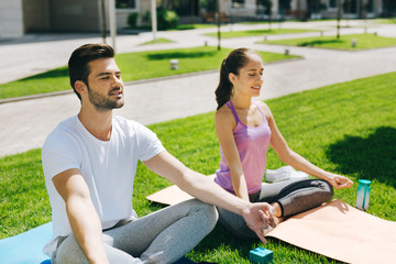 Body awareness. Positive joyful people smiling while practicing yoga together