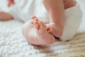 Little feet of a newborn baby on white sheets