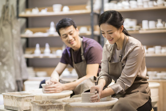 Potter teaching young woman making pottery