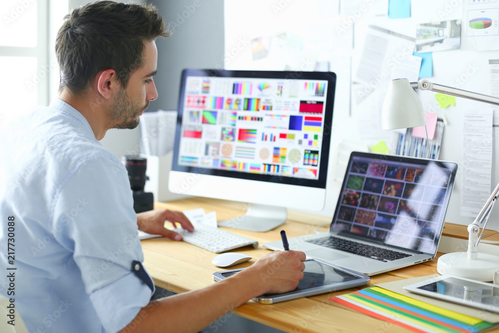 Aufkleber portrait of young designer sitting at graphic studio in front of laptop and computer while working o