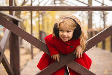 a girl with blond hair plays at the wooden fence