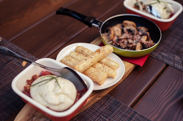 Roasted mushrooms with onion in frying pan over wooden background