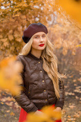 Fototapeta na wymiar girl in a black beret with bright red lips against the backdrop of an autumn garden
