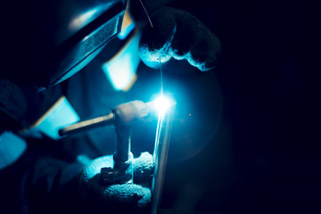 Argon-arc welding welder at the workplace welds the part - obrazy, fototapety, plakaty