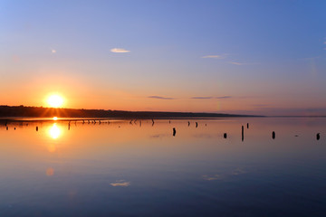 Obraz na płótnie Canvas Sunset over the surface of a quiet estuary.