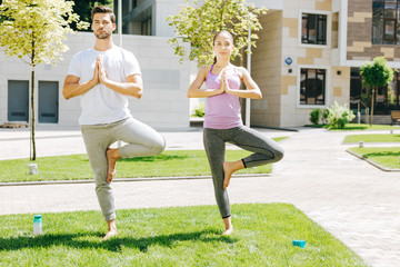 Way to relax. Nice active people staying in a special position while enjoying practicing yoga