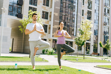 Yoga pose. Positive healthy people standing on one leg while practicing yoga
