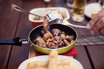 Roasted mushrooms with onion in frying pan over wooden background