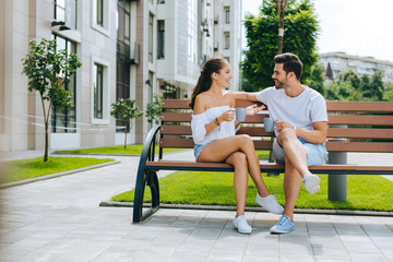 First date. Nice happy people sitting together on the bench while having their first date