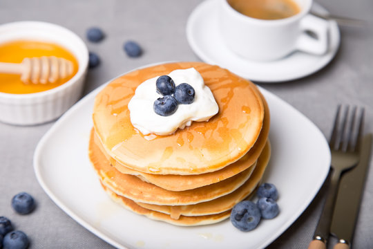 Pancakes with blueberries, sour cream, honey and coffee. Close-up. Selective focus.