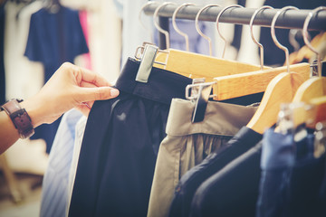 hand of customer choosing skirts in a clothing store
