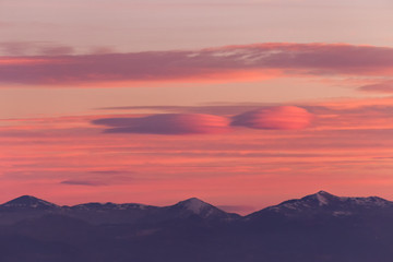 A view of some mountains top, beneath a beautiful, warm colored sky at sunset