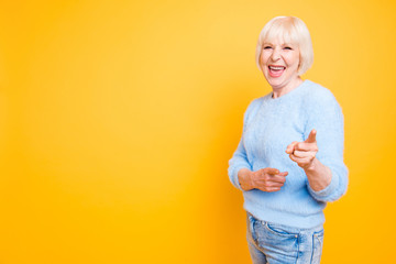 Portrait of confident modern granny pointing two index fingers a