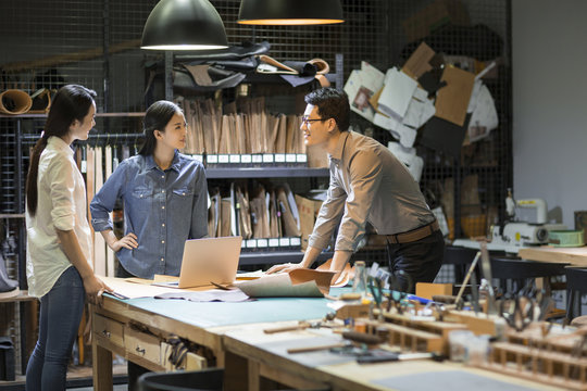 Confident leather craftspeople working in studio