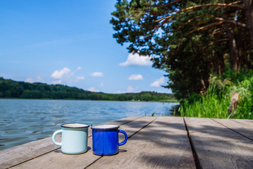 two metal cups with tea. river on background. summer time concept