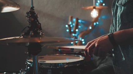 Male Hands Playing Drums with Rods in a Room with Beautiful Lights in the Background. Close Up