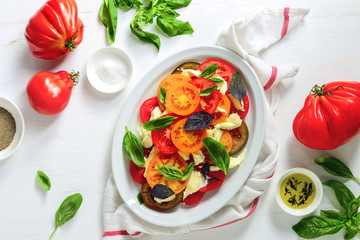 Rustic homemade Italian Caprese salad with torn to pieces mozzarella and various kinds of basil