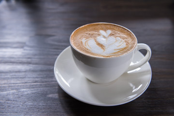 Latte art coffee cup with heart shape on wooden table, top view