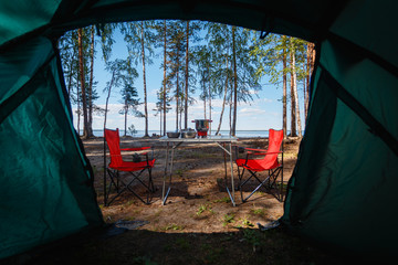 Camping in the middle of the forest, taken from inside the tent. View of the folding table and...