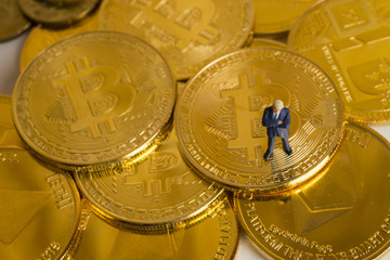 Miniature figure a businessman stands on bitcoin coins currency.