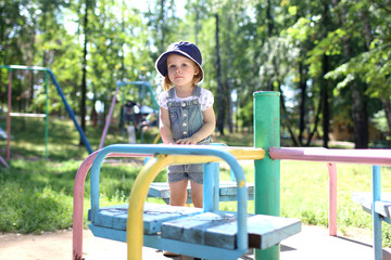 Lovely little toddler girl plays on playpit outdoor in summer