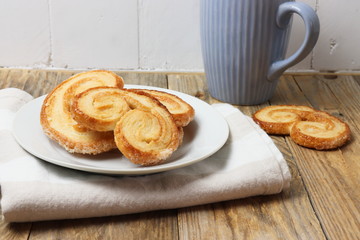Spanish palmiers on a plate with a cup on wooden surface