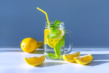 Photo of a transparent glass mug filled with water, sliced ​​lemon and mint leaves with a...