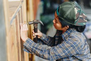 Naklejka premium young woman hammering nail in wall