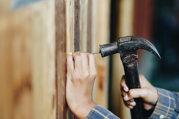 young woman hammering nail in wall