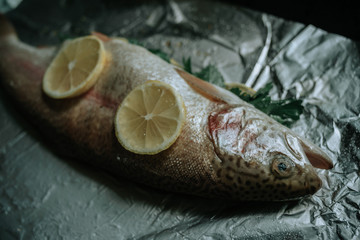 Fresh fish with parsley and lemon on foil prepared for baking