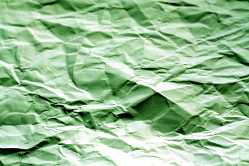 Crumpled sheet of paper with blur effect in green tone.