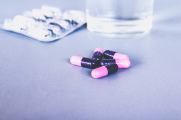 pills and tablets on grey background with bottle and glass