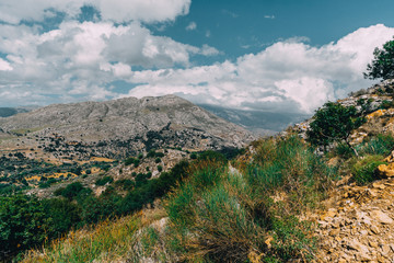 Crete Greece, View on mountains with low hanging clouds and blue sky and green trees. South Crete neat Rethymno, Greece