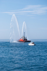 Naval vessel of firefighters with high splashes of sea water