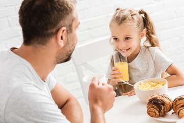 father and daughter having breakfast and looking at each other