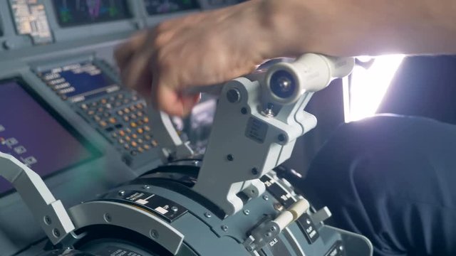Close up of airplane pilot's hand regulating thrust lever handle for engine control during flight.