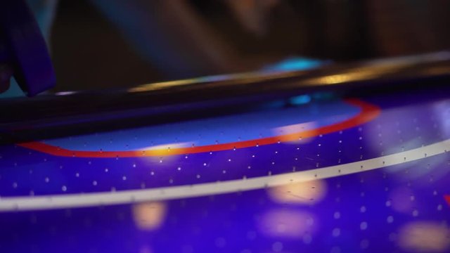 4K shot of a girl accidentally knocking an air hockey puck into her own goal.