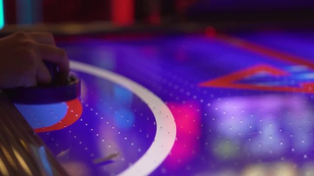 Slo-motion, side shot of a air hockey puck whizzing into the goal right past the player's hand.