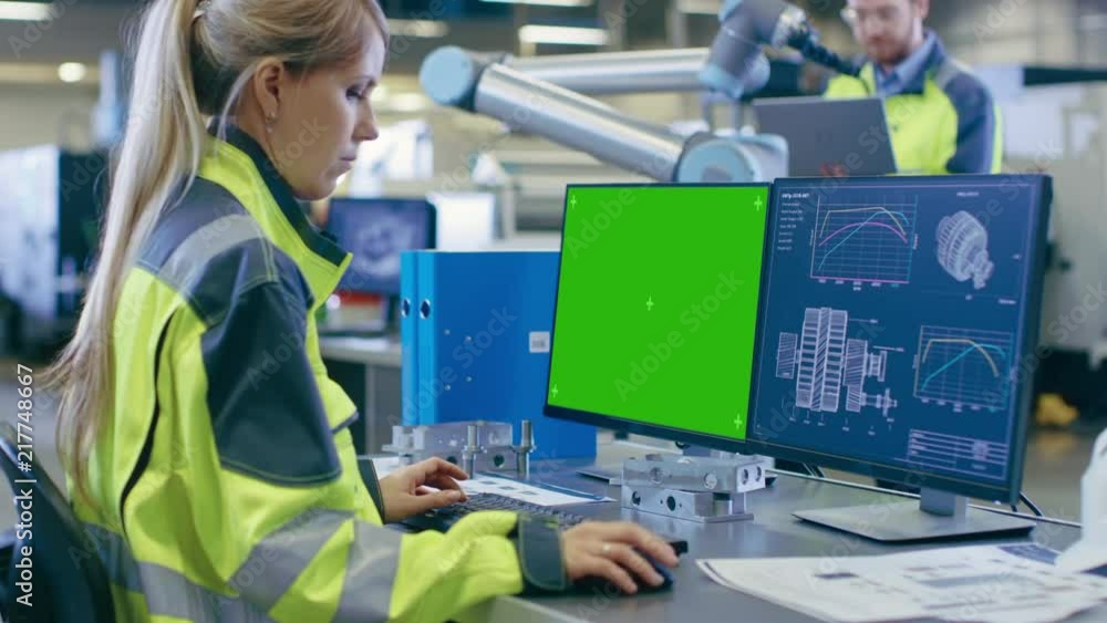 Leinwandbilder At the Factory: Female Chief Engineer Works on the Green Mock-up Screen Personal Computer with Two Displays, Second Display Shows Graphics Blueprint for Engine.
